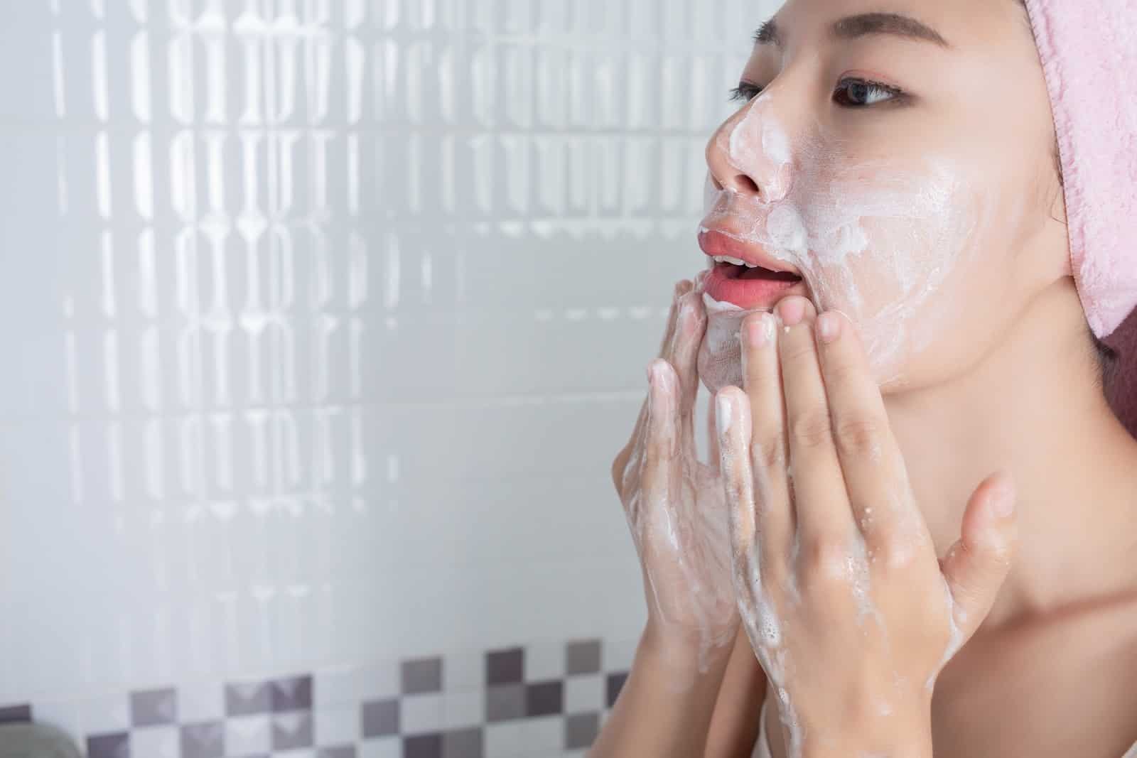a woman cleaning her face thoroughly with facewash